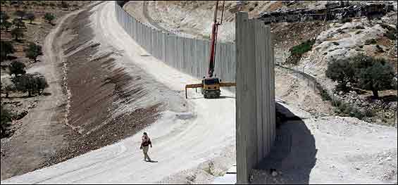 A Palestinian walks by the security fence.  <font size=-2>(Source: AFP)</font>